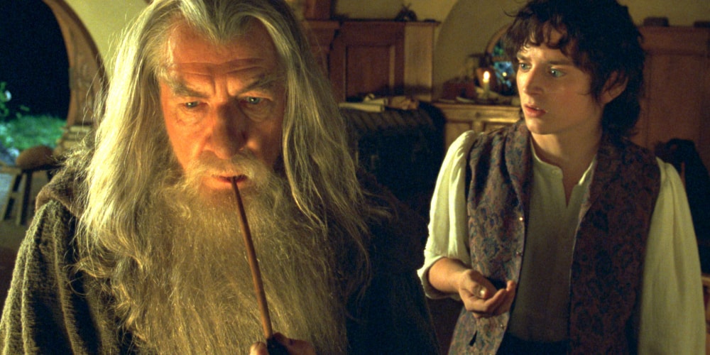 Deux personnages discutent dans une maison, l'un tient une pipe.