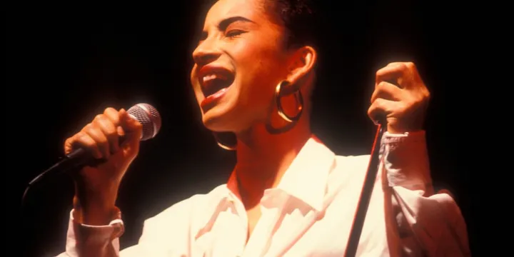 Chanteuse en concert avec micro et chemise blanche.