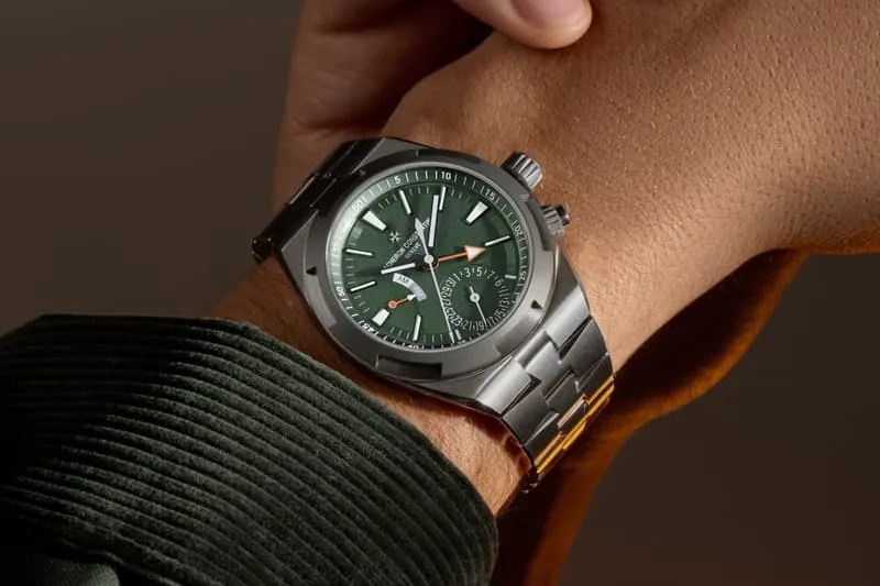 Montre-bracelet en métal avec cadran vert sur poignet.