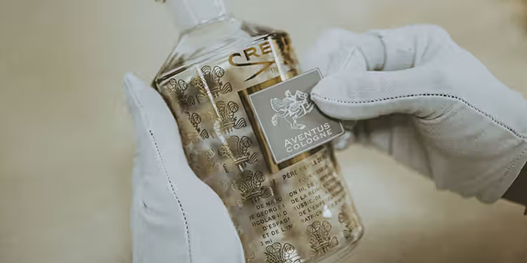 Une bouteille de parfum tenue par des mains gantées.