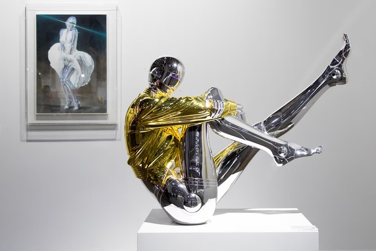 Statue futuriste en métal devant un tableau célèbre dans une galerie.