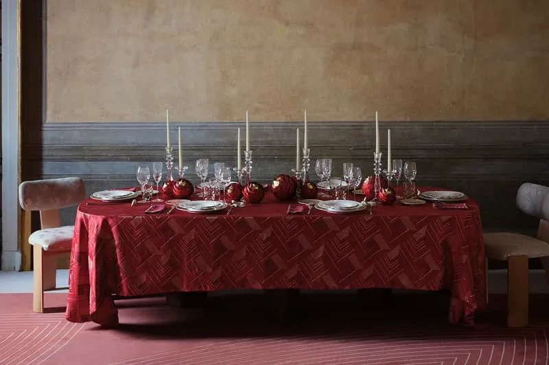 Table élégante avec nappe rouge et bougies, ambiance chaleureuse.