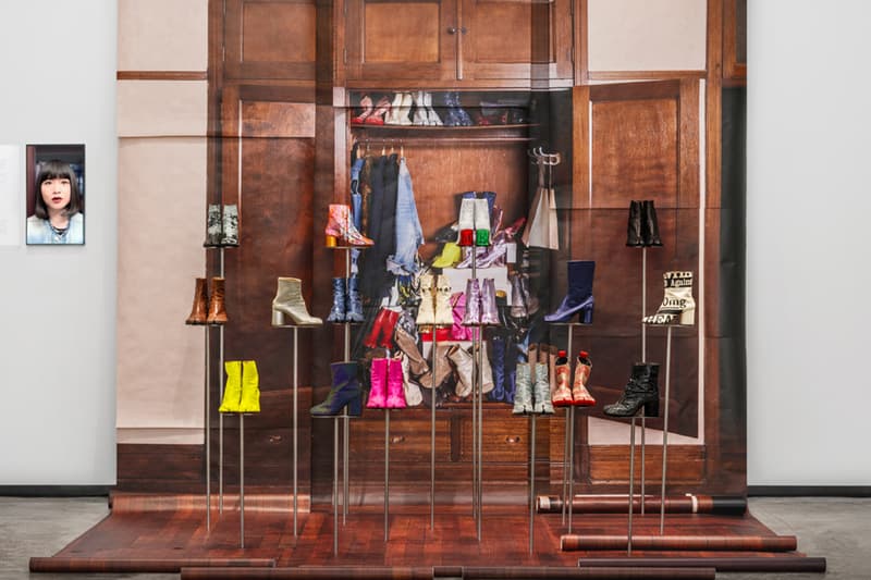 Installation artistique de chaussures devant une photo de dressing moderne.