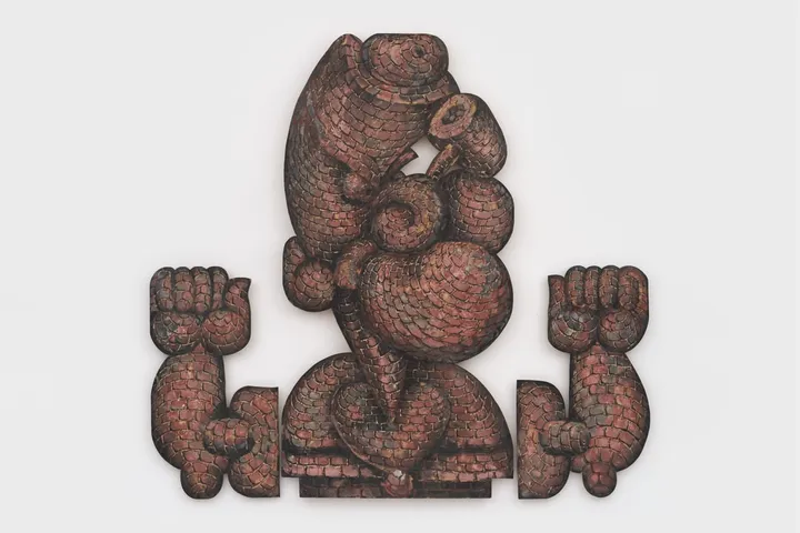 Sculpture de personnage stylé avec muscles proéminents et texture de briques.