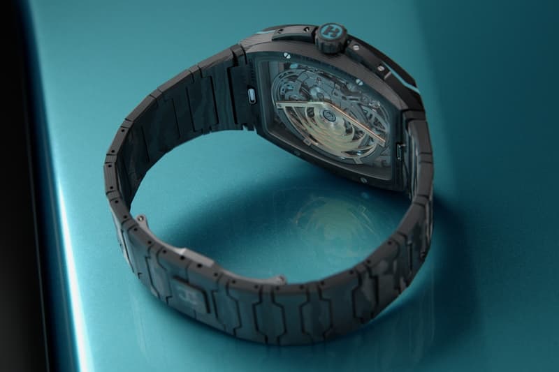 Montre noire avec un bracelet sur fond bleu clair.