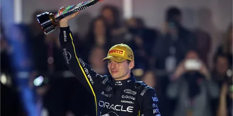Pilote de F1 avec trophée et casquette dorée, porte un costume Oracle.
