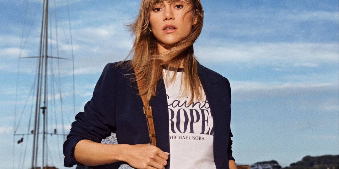 Femme en blazer avec sac à l'épaule, bateau en arrière-plan.