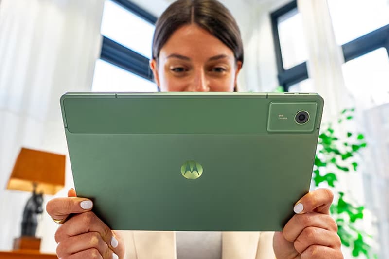 Femme tenant une tablette verte dans un bureau lumineux.