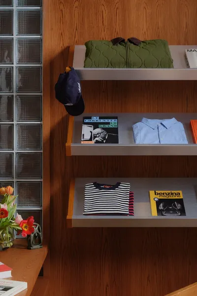 Étagères avec livres, vêtements pliés et casquette exposés.