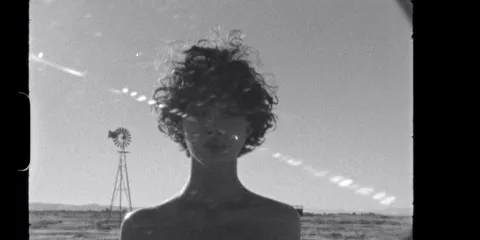 Personne aux cheveux bouclés devant un paysage désertique.