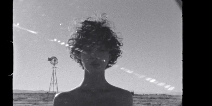 Personne aux cheveux bouclés devant un paysage désertique.