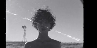 Personne aux cheveux bouclés devant un paysage désertique.