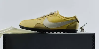 Chaussure jaune avec logo blanc sur boîte noire.