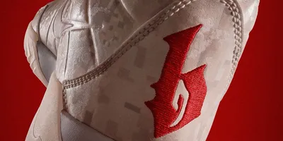 Basket blanche avec logo rouge sur fond rouge.