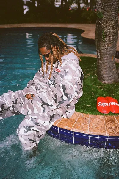 Personne en tenue camouflage au bord de l'eau avec des sandales rouges.