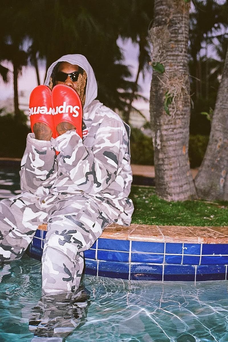 Personne assise au bord d'une piscine portant des vêtements camouflage et des sandales.