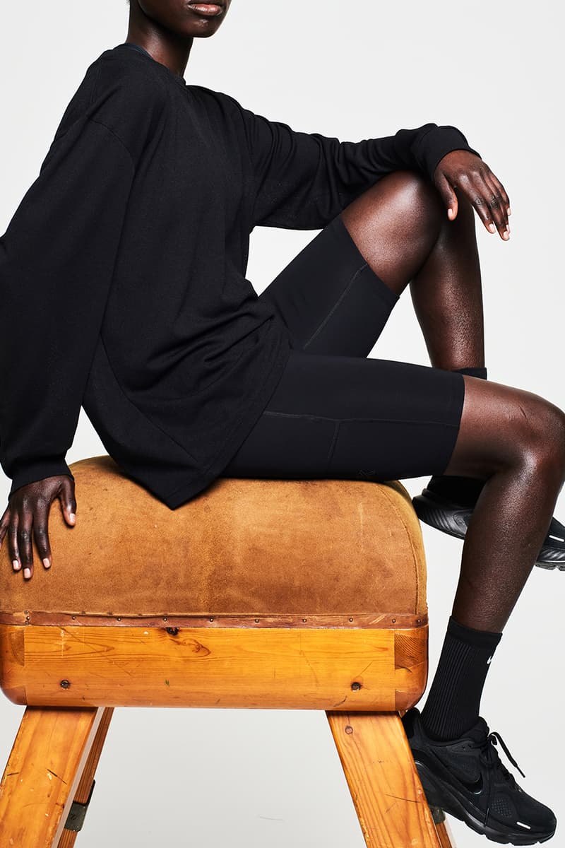 Personne en tenue sportive noire sur un cheval d'arçons en bois.