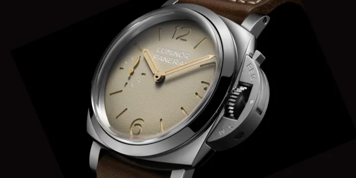 Montre avec cadran beige et bracelet en cuir marron.