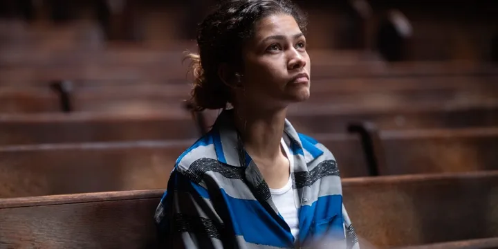Femme assise seule dans une église, regardant vers le haut pensivement.
