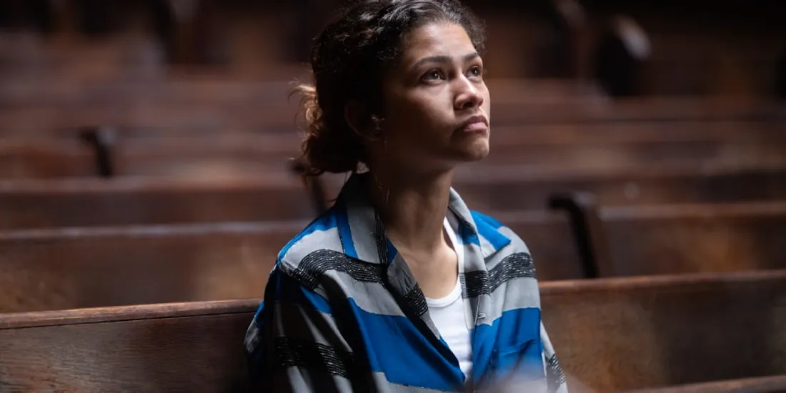 Femme assise seule dans une église, regardant vers le haut pensivement.
