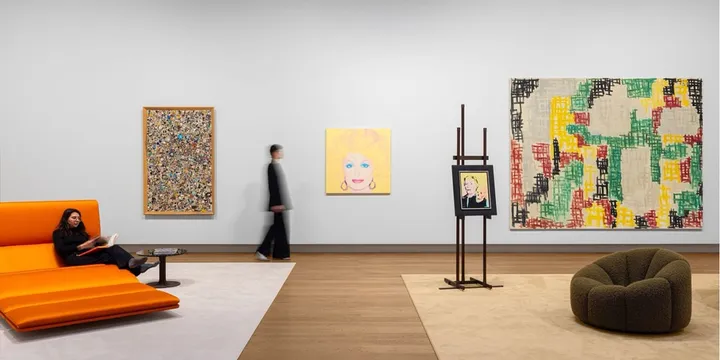Galerie d'art avec œuvres et mobilier moderne, personnes présentes.