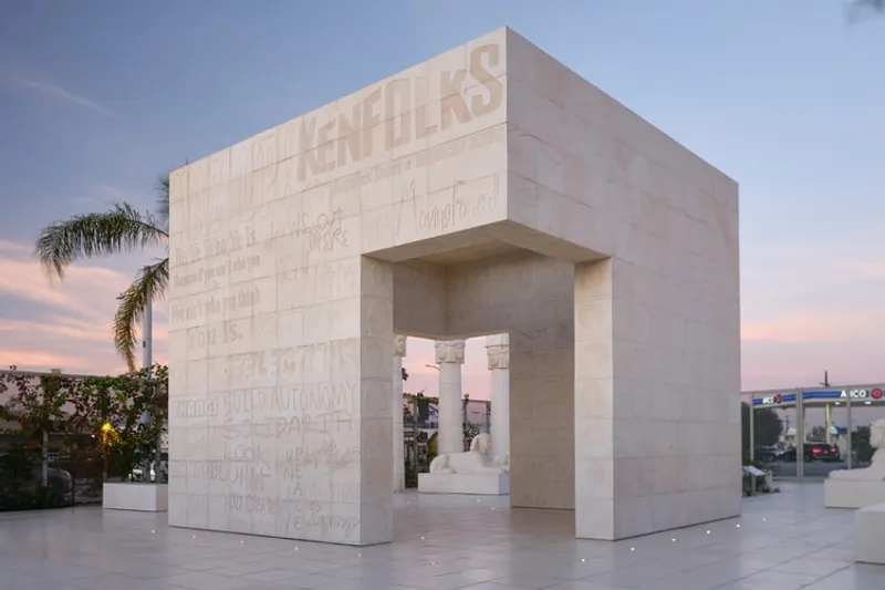 Structure en pierre blanche avec inscriptions dans un cadre urbain.