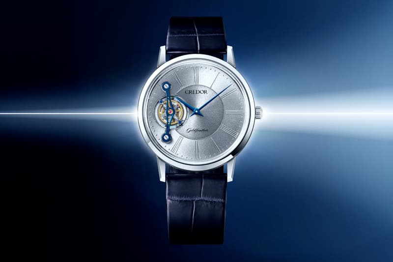 Montre de luxe avec cadran argenté et bracelet en cuir bleu.