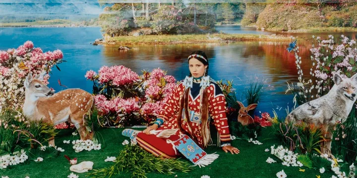 Personne en habit traditionnel devant un paysage floral et lacustre.