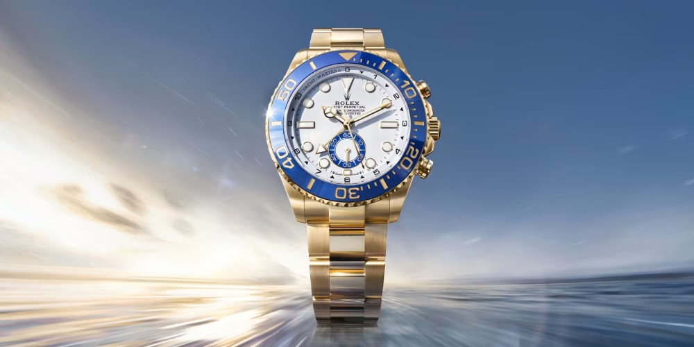 Montre en or avec cadran bleu et blanc, sur fond de paysage flou.