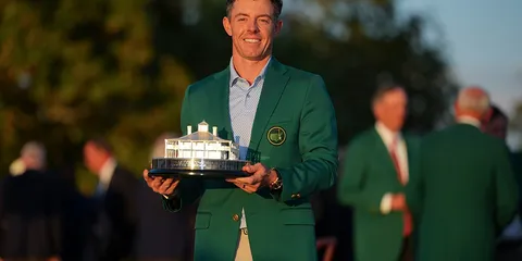Homme en veste verte tenant un trophée lors d'une cérémonie de remise de prix de golf.