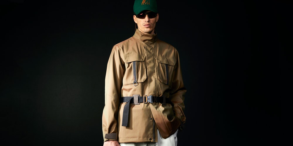 Homme en veste marron avec casquette verte et lunettes noires, fond noir.