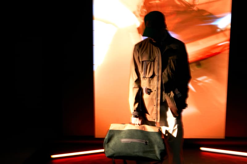 Personne en trench, fond lumineux abstrait, sac vert.