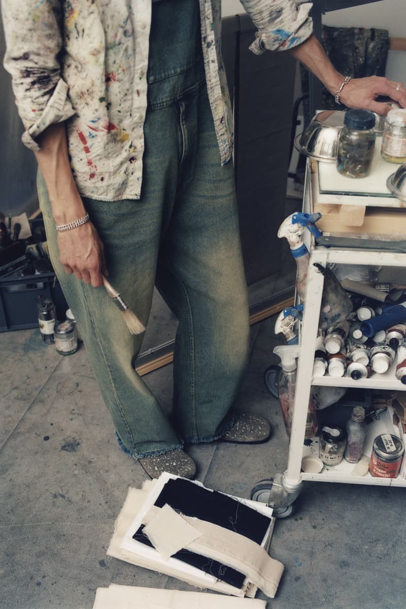 Personne tenant un pinceau dans un atelier d'art avec des toiles et des fournitures.