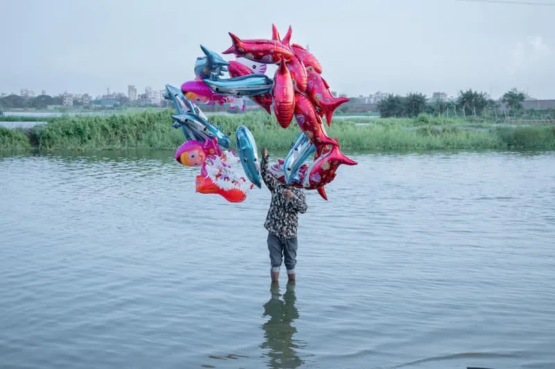 Homme avec des ballons colorés debout dans l'eau.