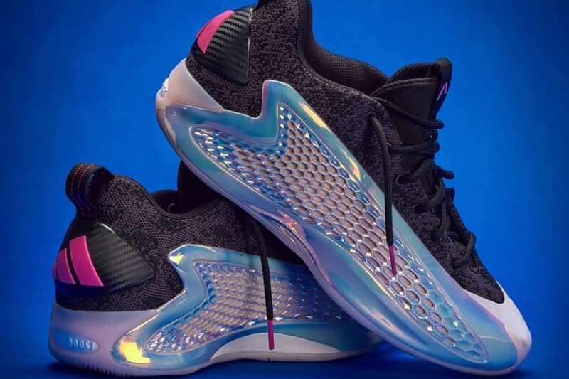 Chaussures de sport noires avec détails holographiques sur fond bleu.