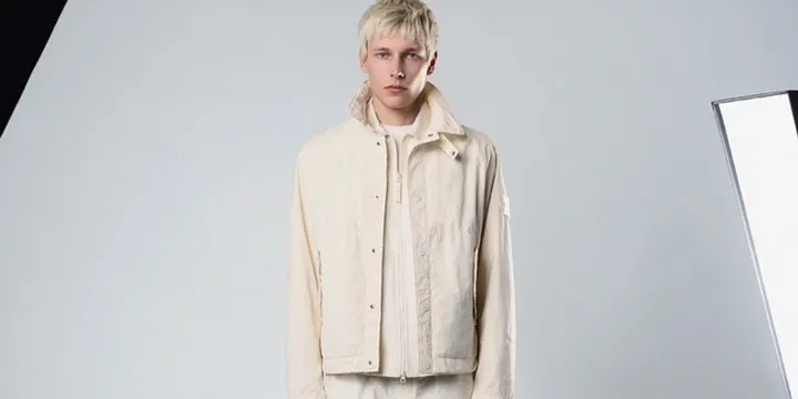 Homme en veste beige sur fond clair, ambiance studio.