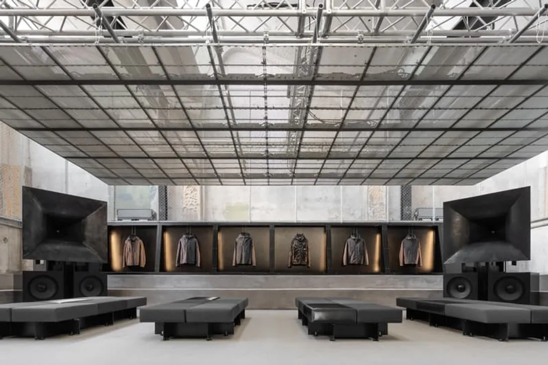 Intérieur de magasin minimaliste avec vêtements exposés et grands haut-parleurs.