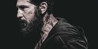 Homme barbu avec capuche, éclairage sombre.