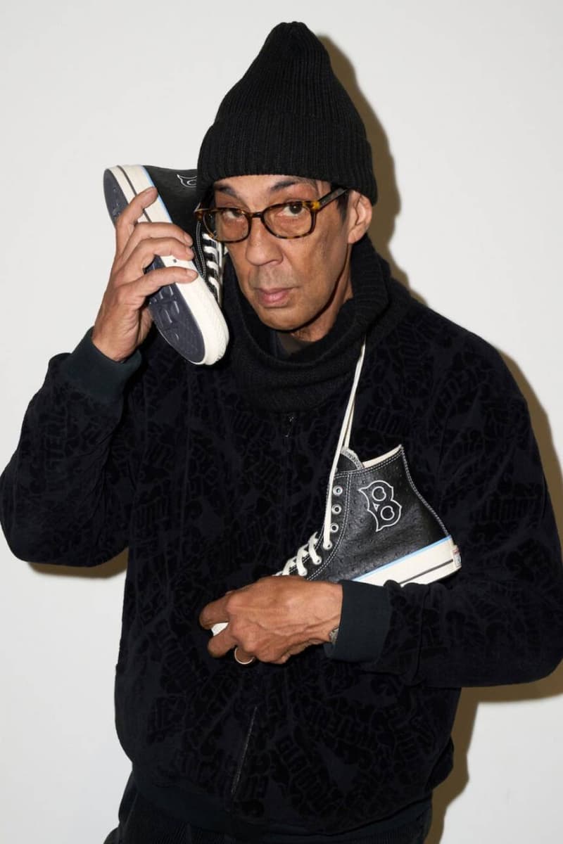 Homme avec bonnet, tenant des chaussures au téléphone.