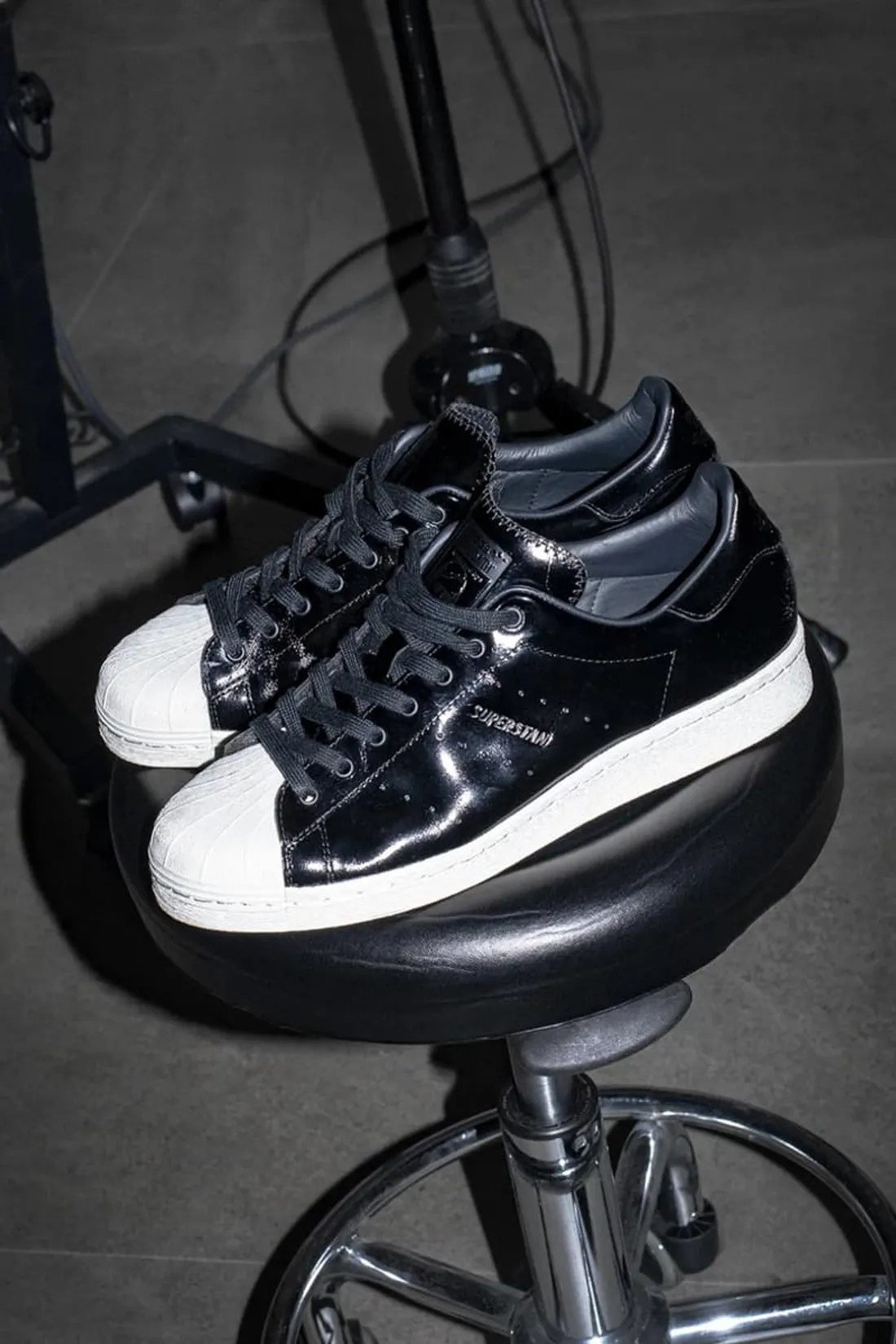 Chaussures noires et blanches sur un tabouret noir.