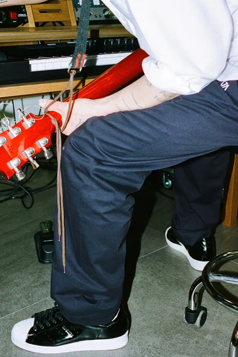 Personne jouant de la guitare rouge avec des chaussures noires et blanches.