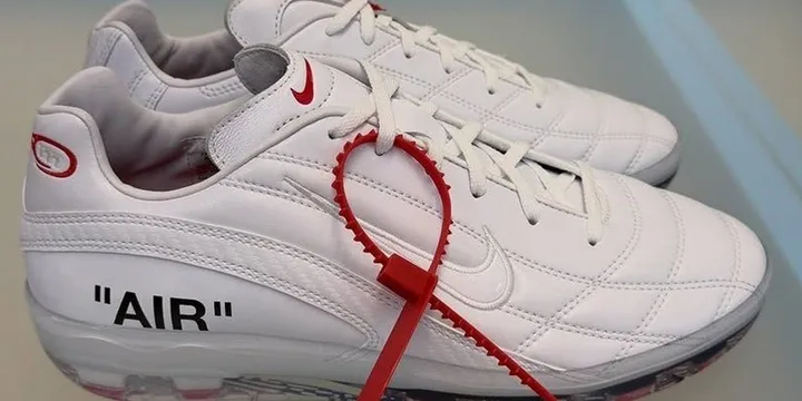 Chaussures blanches avec logo, TEXTE et attache rouge.