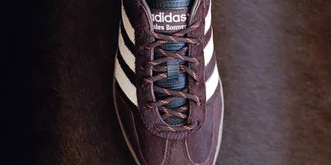 Chaussure Adidas marron avec rayures blanches et lacets marron.