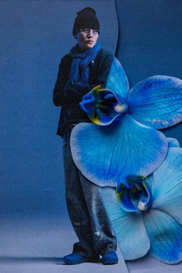 Homme en vêtements bleus avec fleurs bleues sur un fond également bleu.