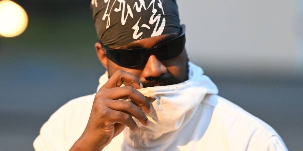 Personne avec lunettes de soleil et bandana, portant un vêtement blanc.