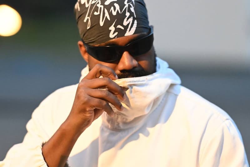 Homme avec lunettes de soleil et bandana, vêtu de blanc.