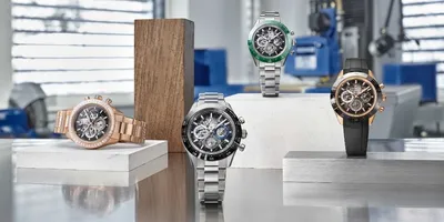 Quatre montres sur socles en bois et métal dans un atelier industriel moderne.