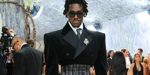 Homme élégant en tenue formelle avec lunettes de soleil lors d'un événement.
