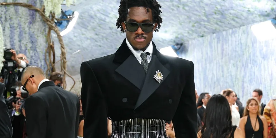 Homme élégant en tenue formelle avec lunettes de soleil lors d'un événement.