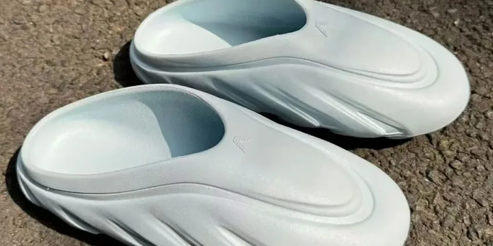 Paire de chaussures blanches sur sol asphalté.